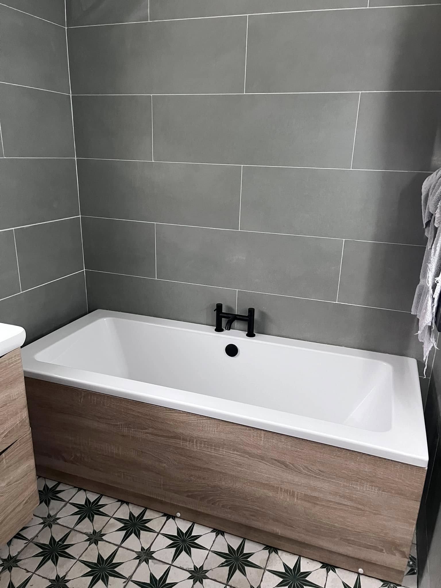 Bath with grey tiles and patterned floor